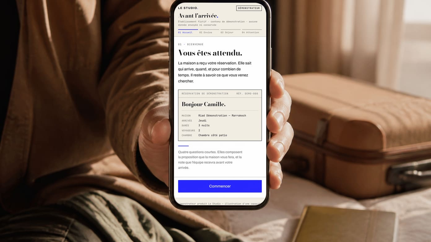 Voyageur adulte tenant un téléphone près d'une valise et d'un carnet, dans une lumière de départ.