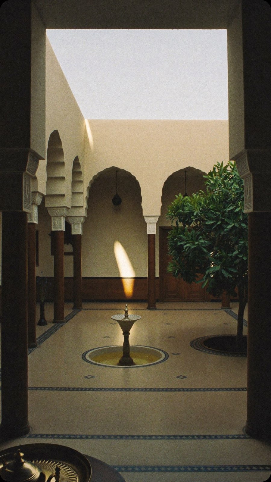 Plan large d'un patio de riad, composition générique : arcades, fontaine centrale, oranger.